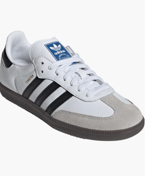 A close-up studio shot of the Adidas Samba OG sneaker in white leather with signature black stripes, a grey suede toe overlay, and a classic gum rubber sole.