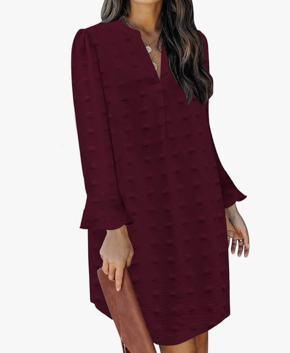 A woman wearing a burgundy long-sleeve flowy mini tunic dress with a V-neck and ruffled cuffs, styled with a brown leather clutch for a professional yet comfortable hybrid work outfit.