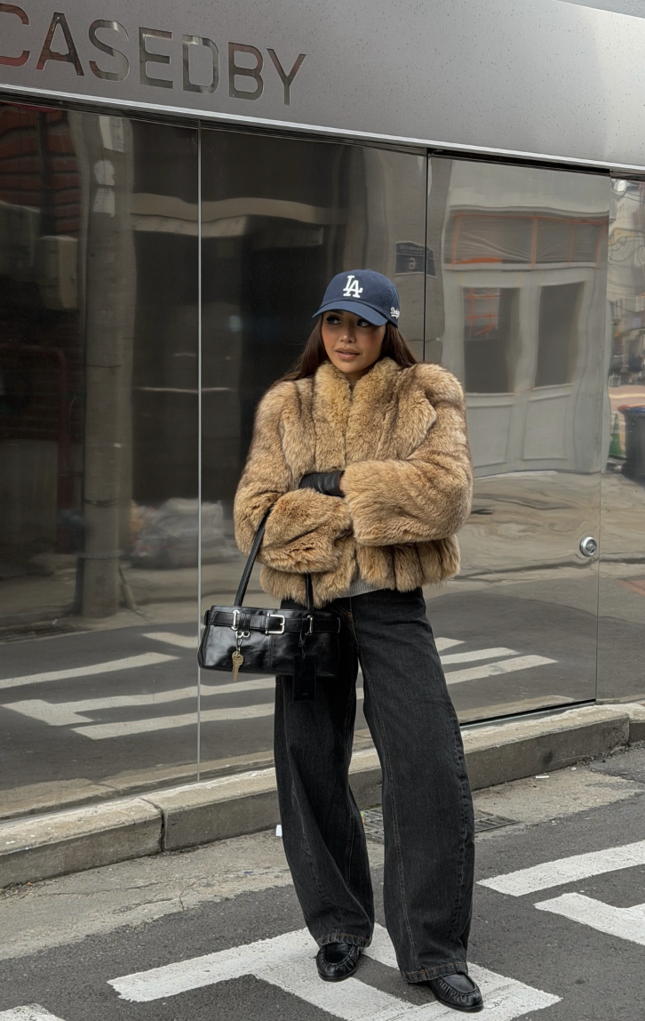 A tan textured jacket with dark wide-leg jeans.