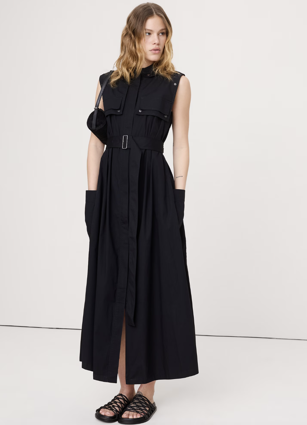 A woman wearing a black stretch-cotton utility maxi dress with a collared neck and button-front details.