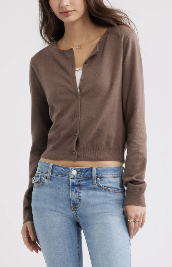 A close-up shot of a model wearing a fitted chocolate brown crewneck cotton-blend cardigan, buttoned up and paired with high-waisted blue wide-leg jeans.
