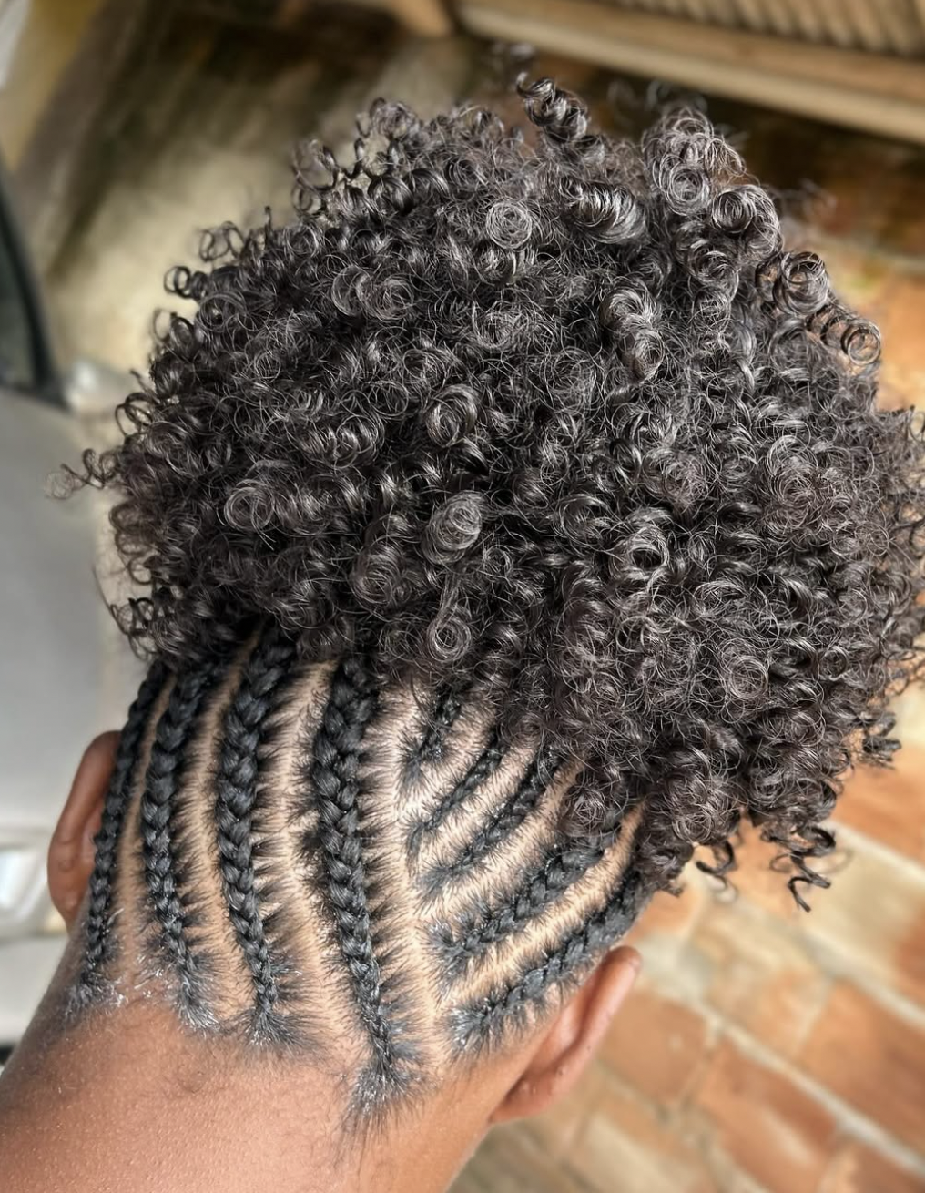 A woman with long locs styled into a voluminous crown puff at the top of her head, showcasing how the height balances a narrower forehead on a diamond face shape.