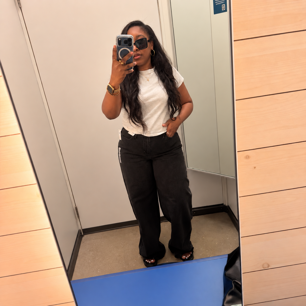 Woman in a dressing room mirror wearing Old Navy's Mid-Rise Wow Baggy Wide-Leg Jeans in black, Long length, with a white tee.