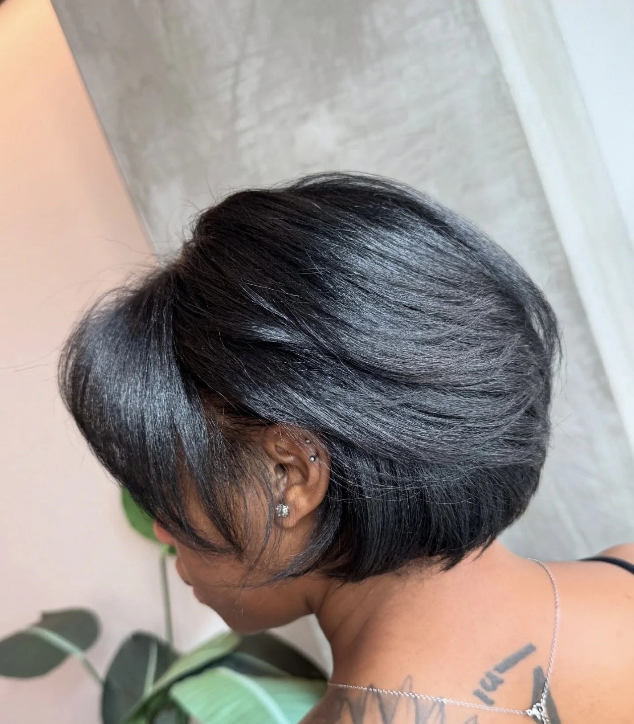 A woman with a square face shape featuring a tapered bob that is shorter in the back and longer in the front, creating a soft framing effect along the jawline.