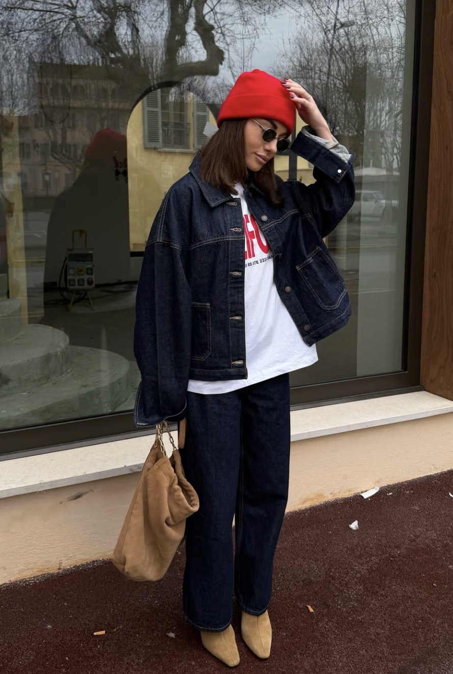 A person wearing tan suede pointed-toe boots with dark wash slim-straight jeans, a white t-shirt, and an oversized denim jacket, carrying a brown slouchy bag.