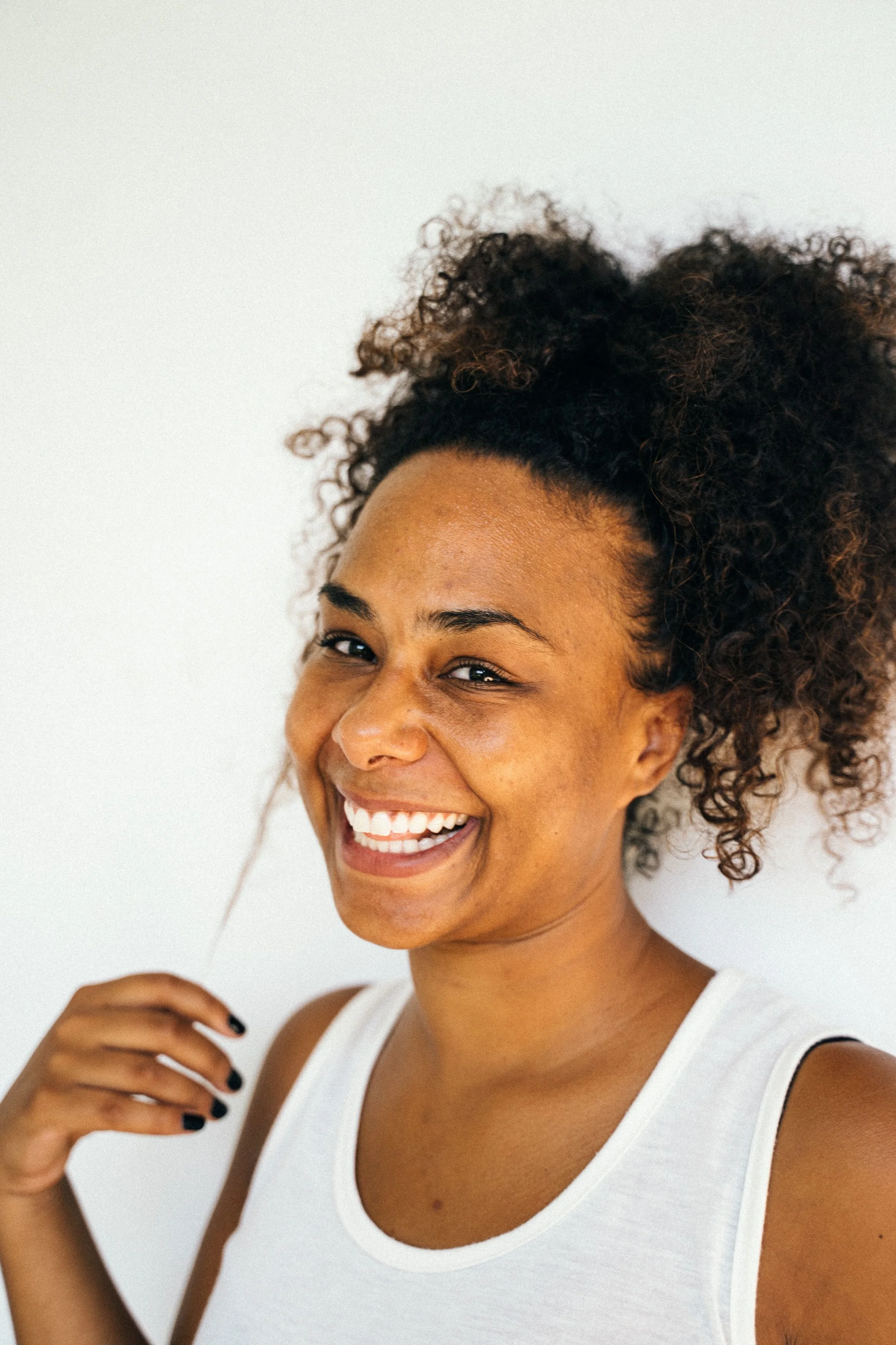 Natural coily hair with lightweight hair oil being applied to the ends