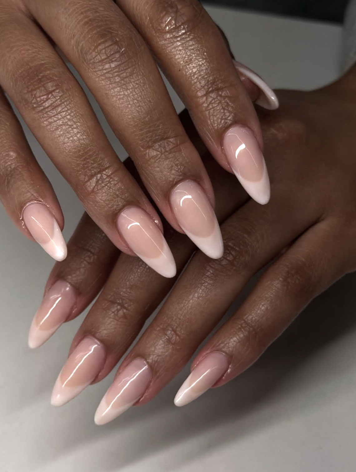 Short natural nails with thin taupe French tips on a sheer base.