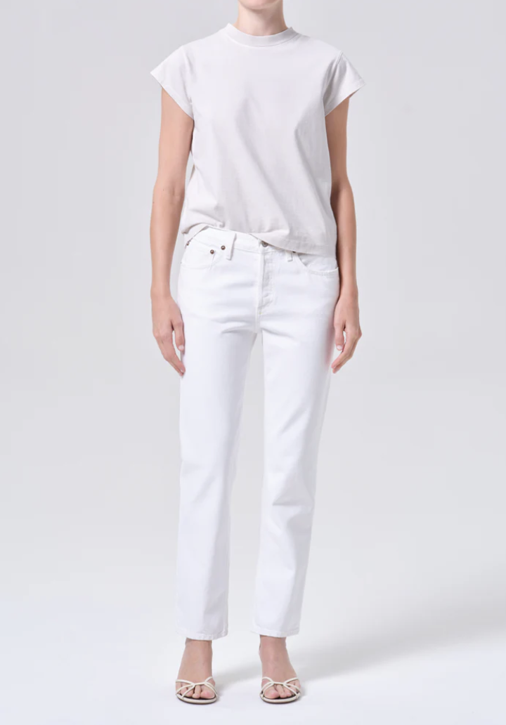 Woman wearing high-waisted white straight-leg jeans with white strap sandals.
