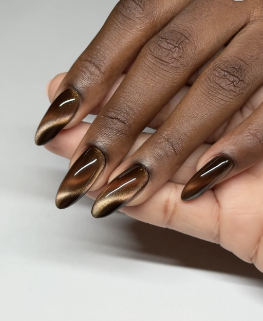 caramel aura nails manicure photographed close up on hands.