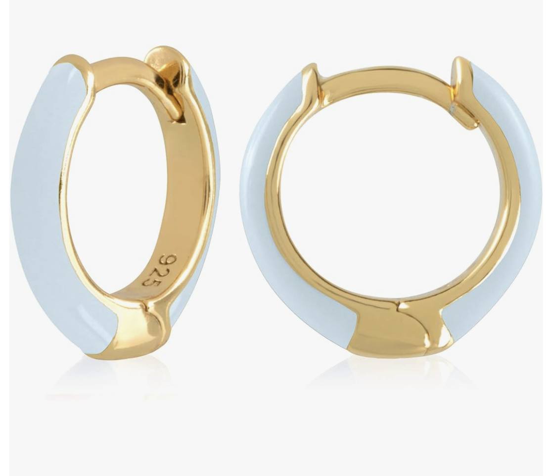 A pair of 14K gold plated huggie hoop earrings featuring light blue enamel inlay on a transparent background.