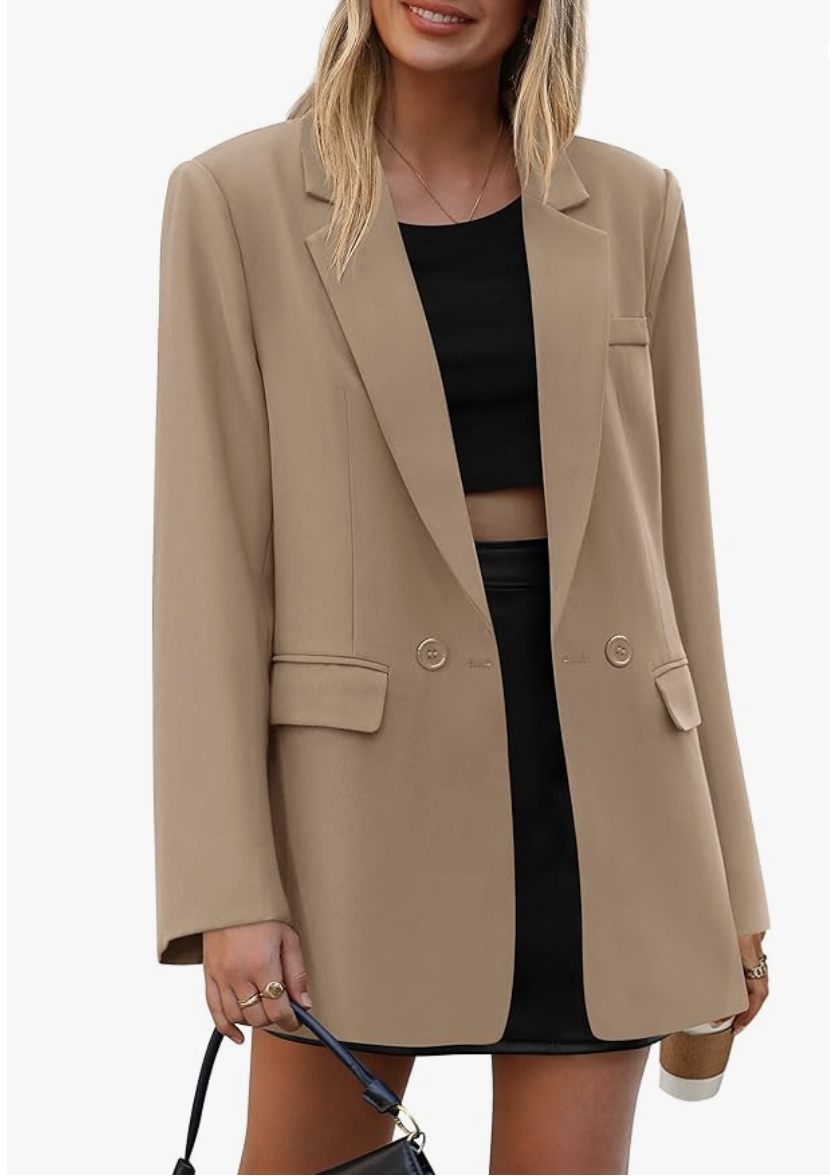 A woman wearing a tan structured lapel blazer over a black mini dress, showcasing a polished and versatile investment piece for a 2026 capsule wardrobe.