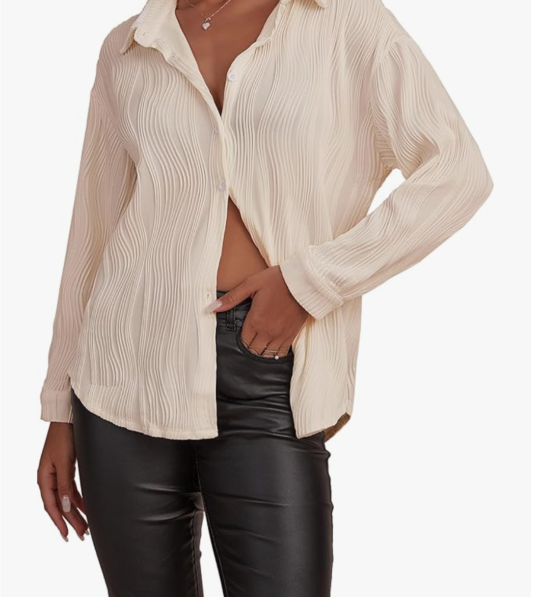 A woman wearing a cream-colored, pleated Textured Button Down Long Sleeve shirt unbuttoned over a black top and dark trousers, highlighting a versatile professional layer for an Amazon work capsule.