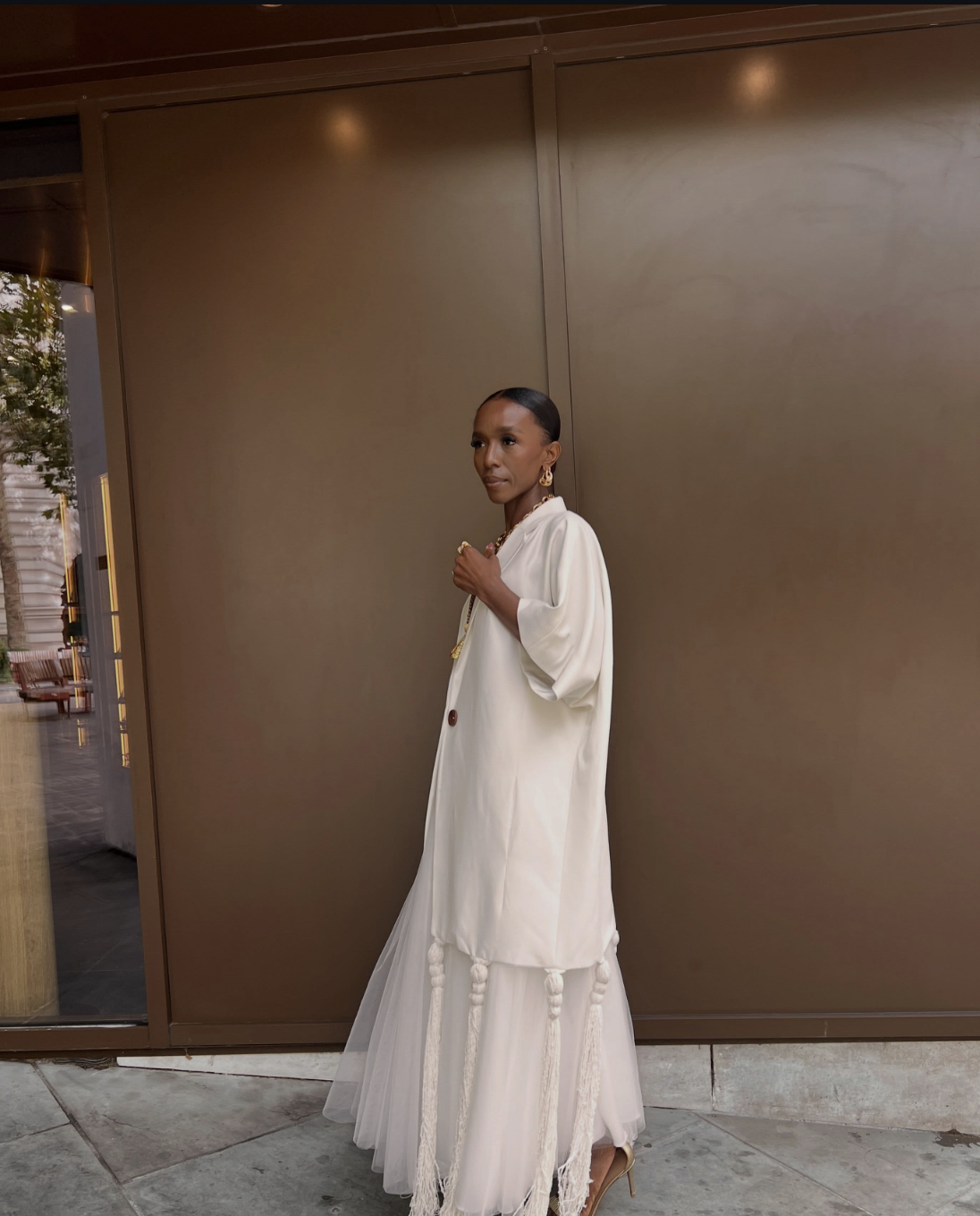 Woman wearing an all-cream outfit with a tiered midi skirt, oversized shirt and heeled sandals