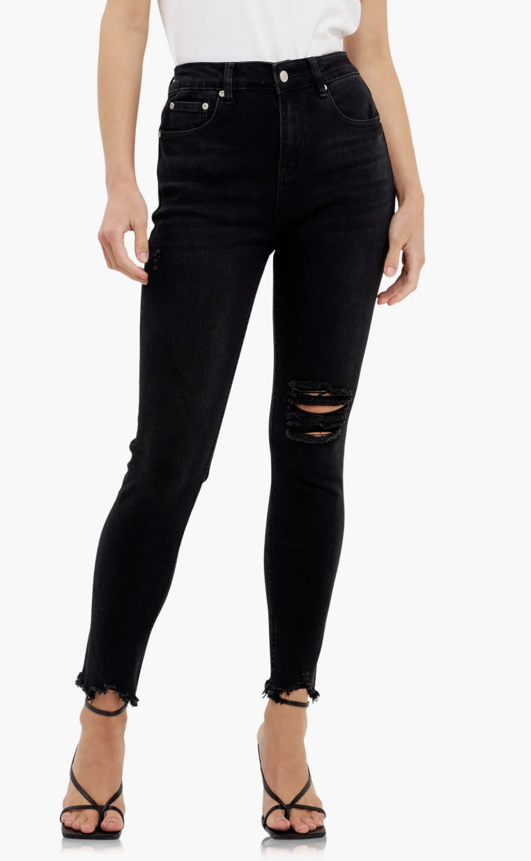 A fashion editor-approved guide on what shoes to wear with cropped pants, featuring black raw-hem skinny jeans paired with minimalist black strappy stiletto heels for a modern, edgy look.