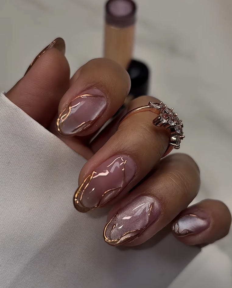 : Close-up of lace nail art on sheer almond-shaped nails featuring delicate gold metallic swirling patterns and 3D textured lines.