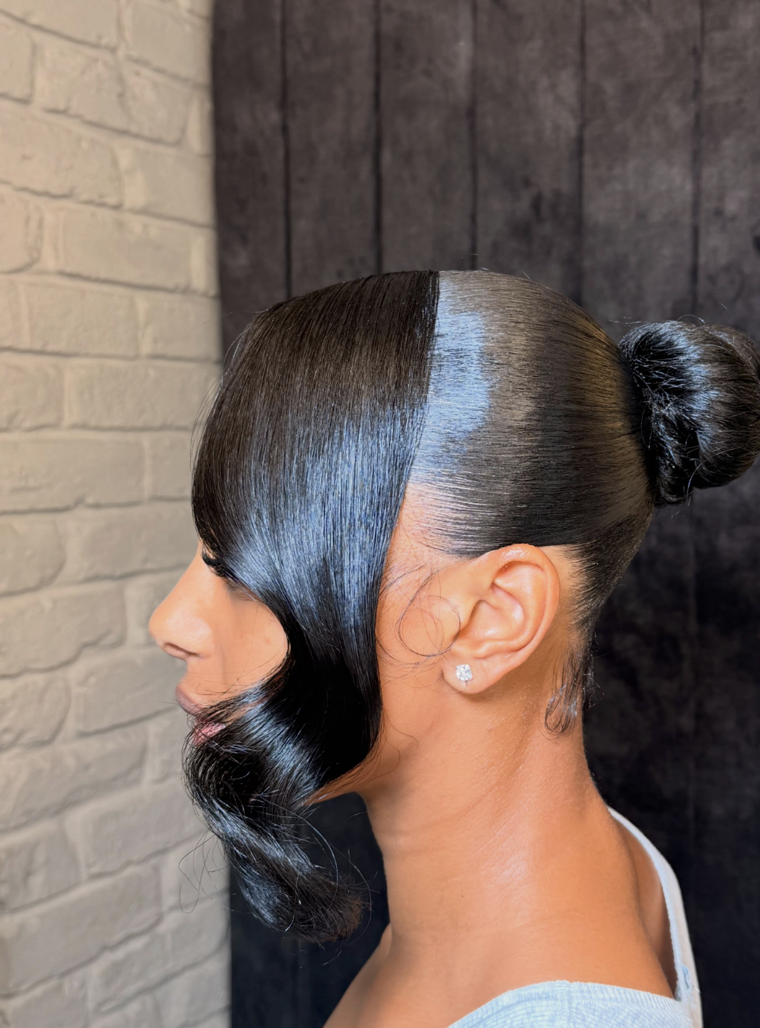 Woman wearing long curtain bangs with a soft bun with soft face-framing movement