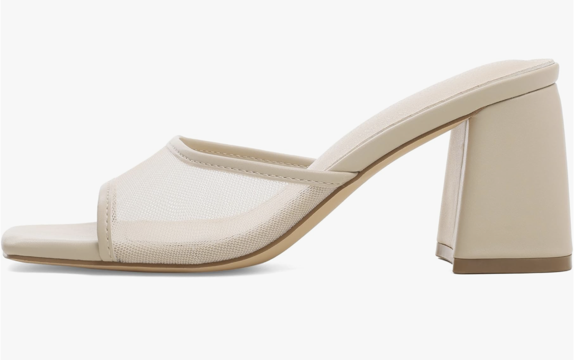 A side profile view of a chic cream-colored mule sandal featuring a sheer mesh front strap, a square toe, and a comfortable low block heel.