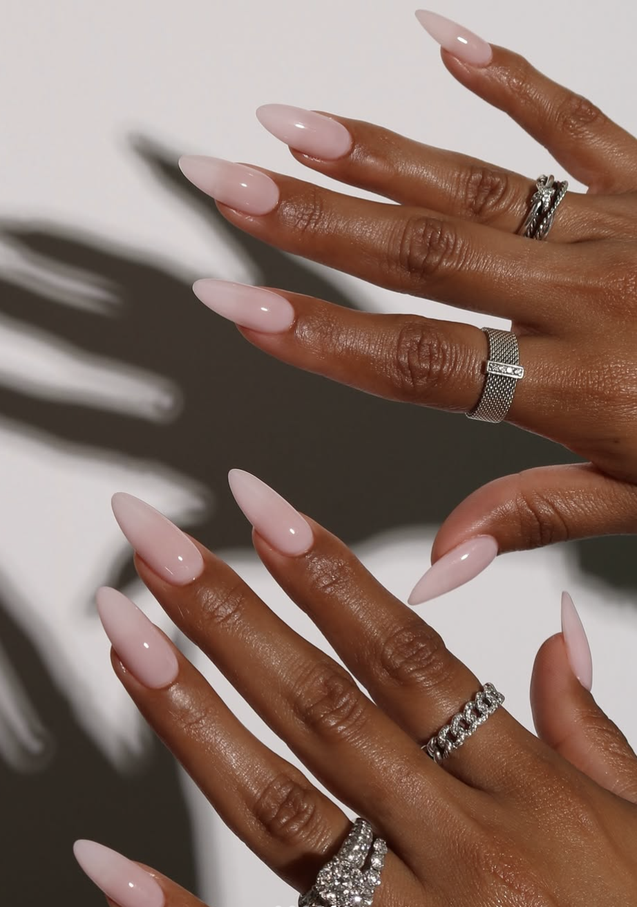 Long, elegant almond-shaped nails showcasing a flawless, high-gloss sheer pink base coat.