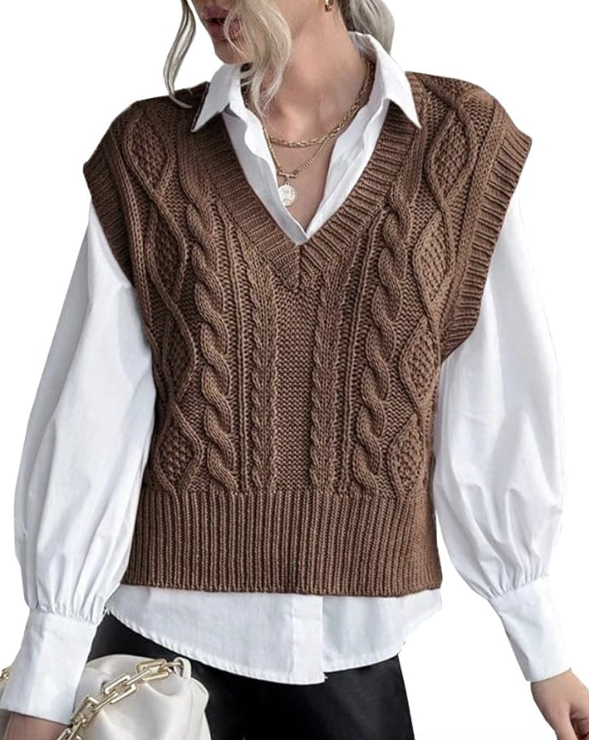 A close-up of a person wearing a brown cable-knit V-neck sweater vest layered over a crisp white long-sleeve button-down shirt.