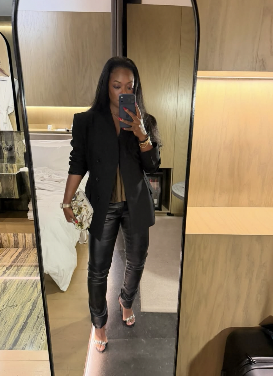Woman wearing black slim leather pants, a black double-breasted blazer, satin camisole and metallic strappy heels
