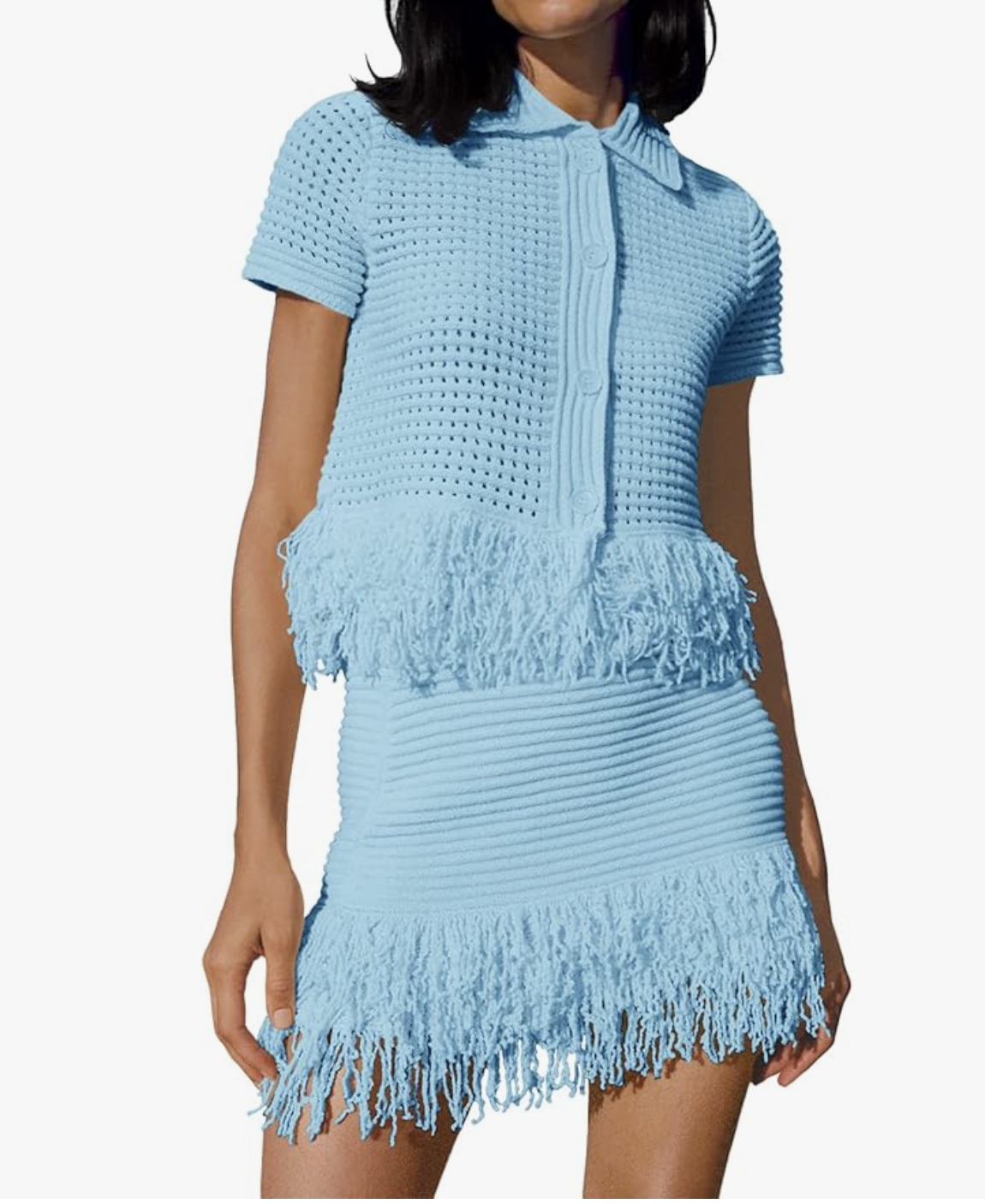 A woman wearing a matching light blue knit set featuring a short-sleeve button-down cardigan shirt and a matching mini skirt, both finished with playful fringe trim along the hems.