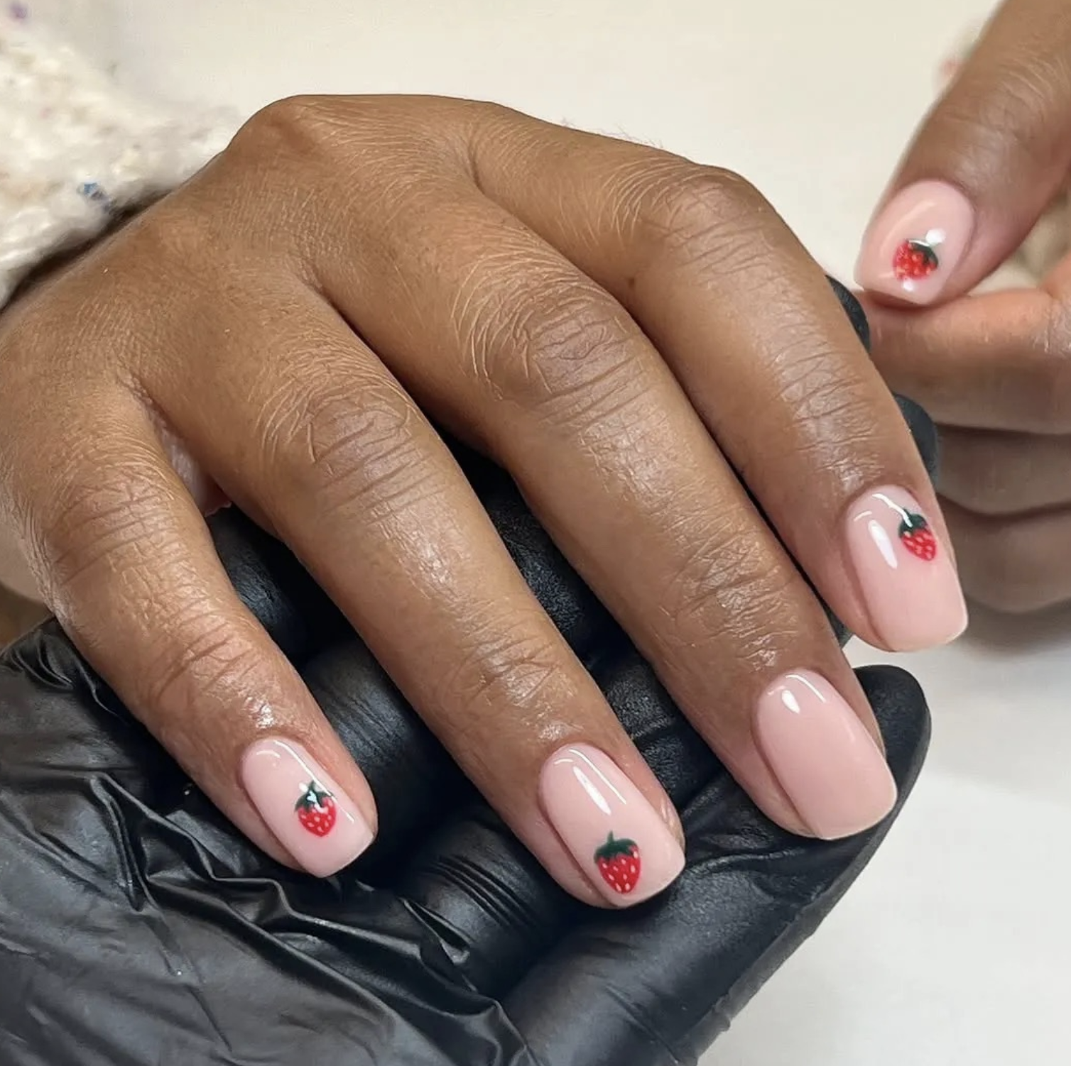 Chocolate-brown manicure with one sheer pink nail featuring a small chocolate-dipped strawberry.