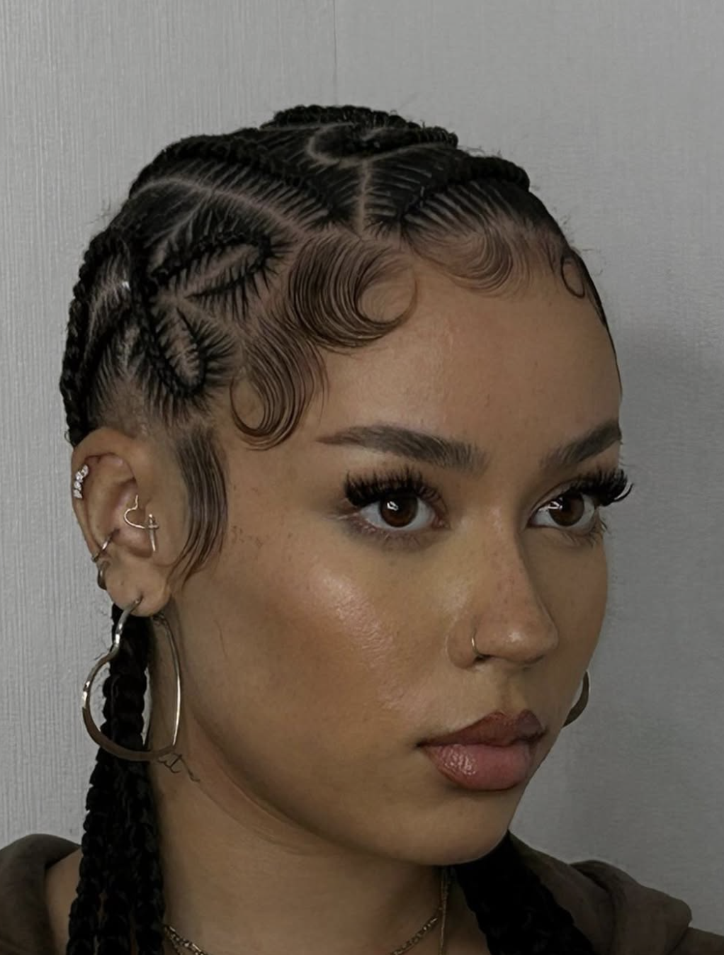 Curved feed-in cornrows with an artistic swooping part pattern across the scalp.