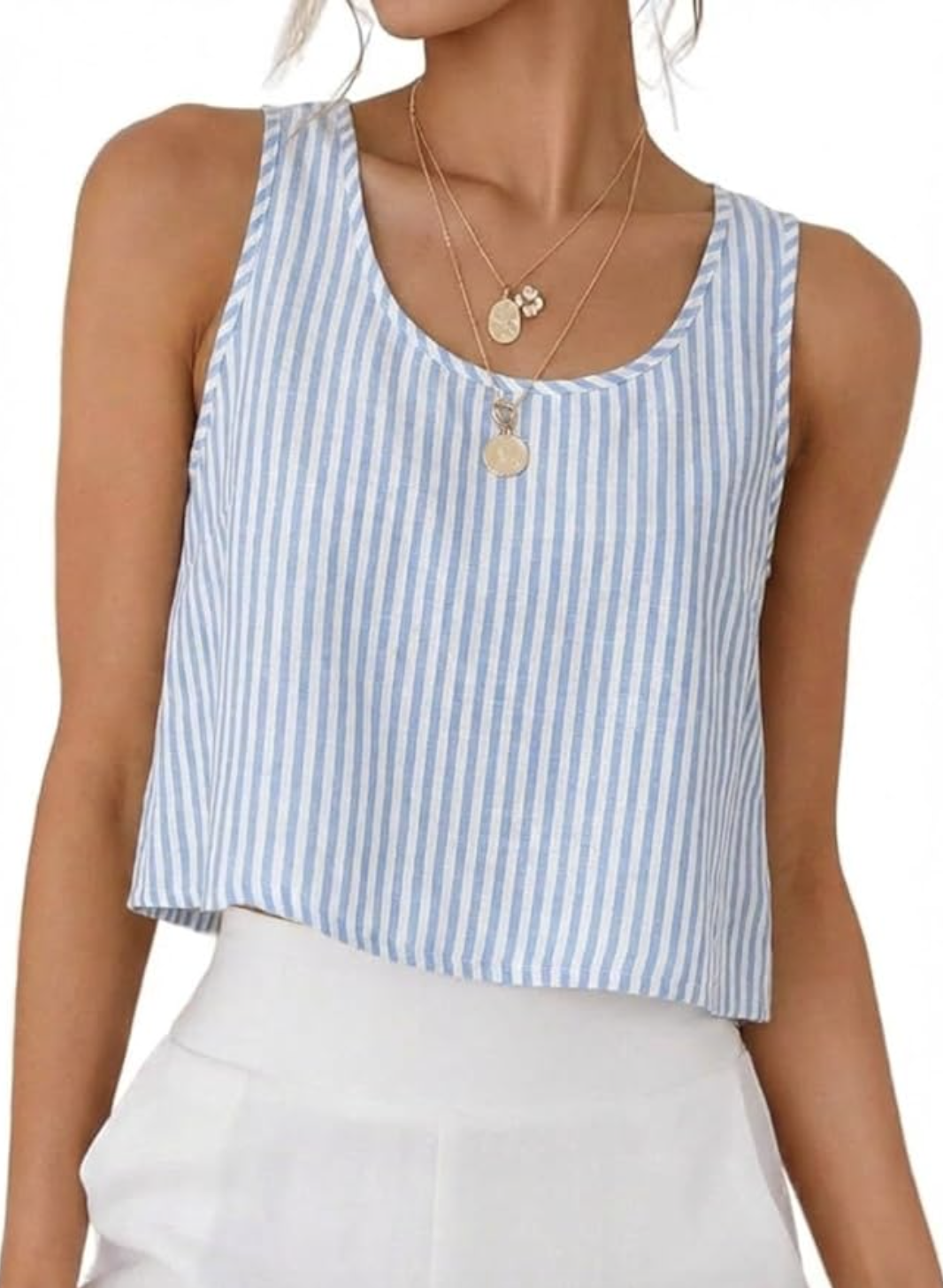 A close-up view of a casual summer outfit featuring a light blue and white vertical striped linen tank top paired with high-waisted white trousers.