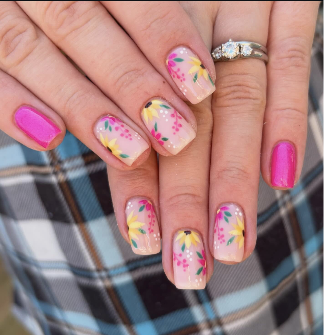 Square-shaped nails with a nude base, featuring hand-painted sunflowers and green leaves on the middle and ring fingers, paired with a solid vibrant magenta-pink polish on the pinky.