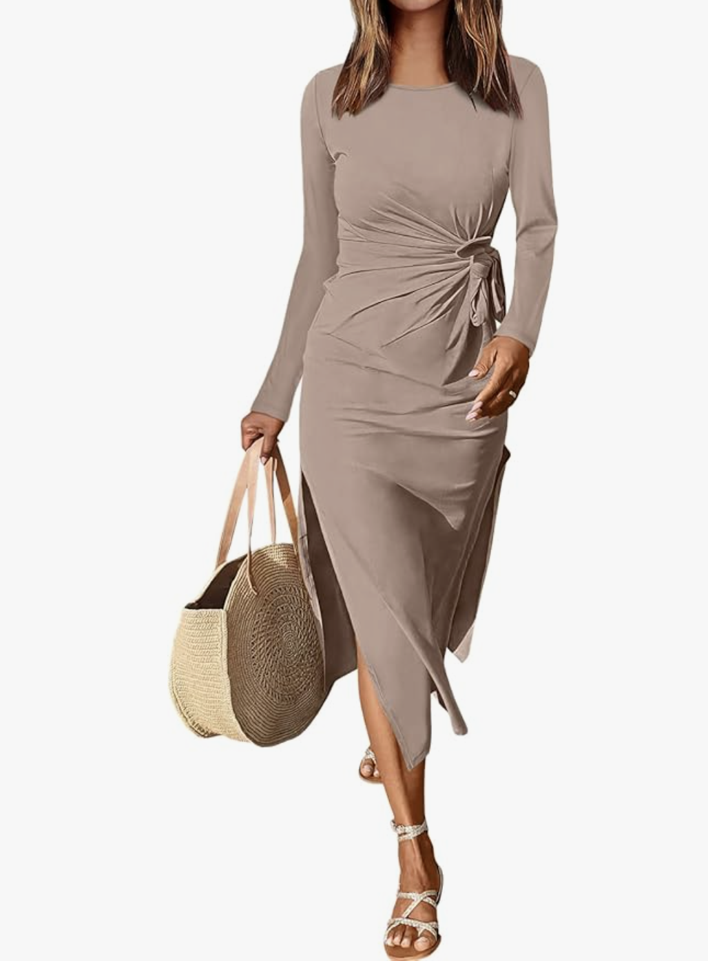 A woman wearing a taupe-colored long-sleeve midi shirt dress with a cinched waist and side knot detail, styled with a straw tote bag for a sophisticated spring look.