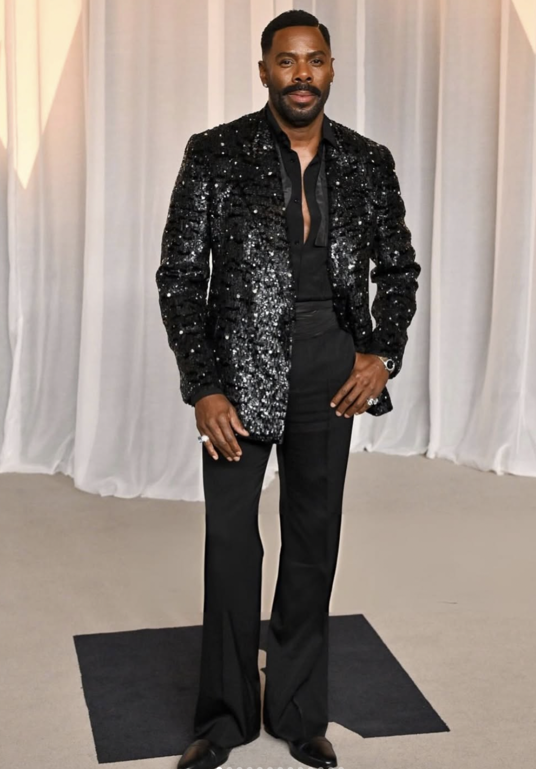 Colman Domingo at the 2026 Academy Museum Gala in a custom Valentino black sequined jacket, open black silk shirt and flared black trousers.