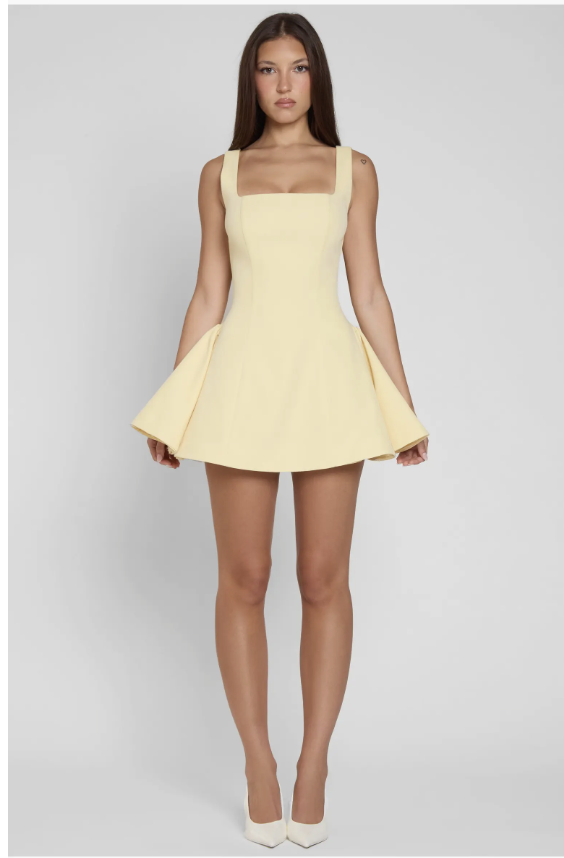 A woman wearing the LEAU Ysabelle babydoll corset mini dress in cream, featuring a structured bodice and a short, flared skirt.