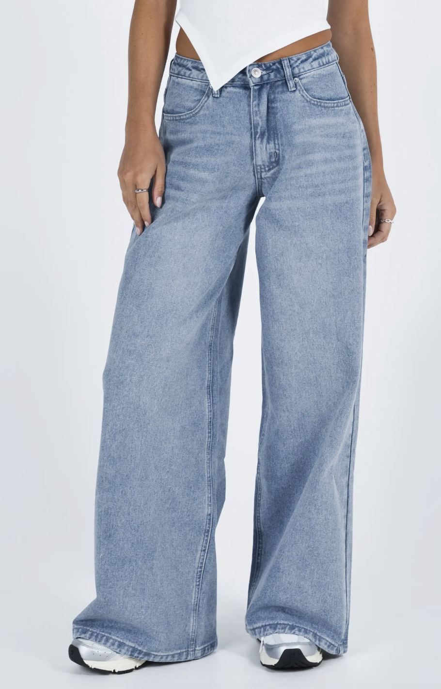 A pair of light blue mid-rise wide-leg jeans styled with a white pointed-hem top and a silver ring.