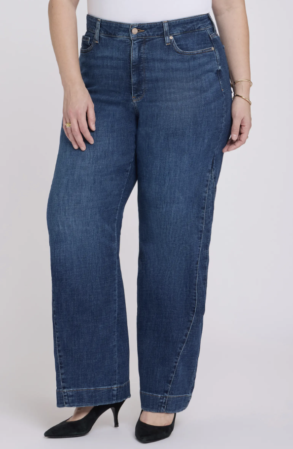 Woman wearing NYDJ Teresa side godet wide leg jeans in a medium blue wash showing the flared leg and high-rise fit.