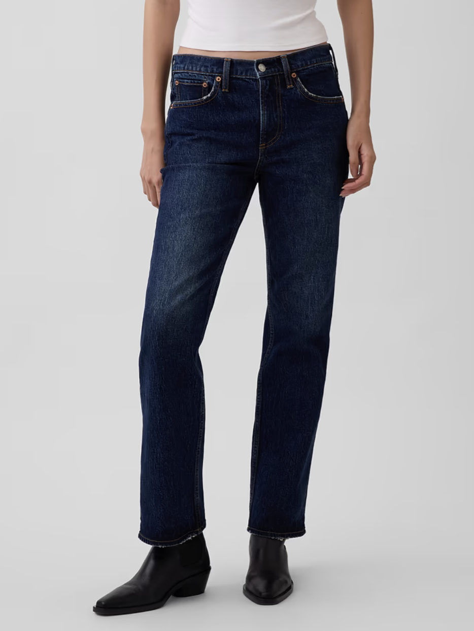 Model wearing high-waisted dark-wash straight-leg jeans paired with black leather boots on a white background.