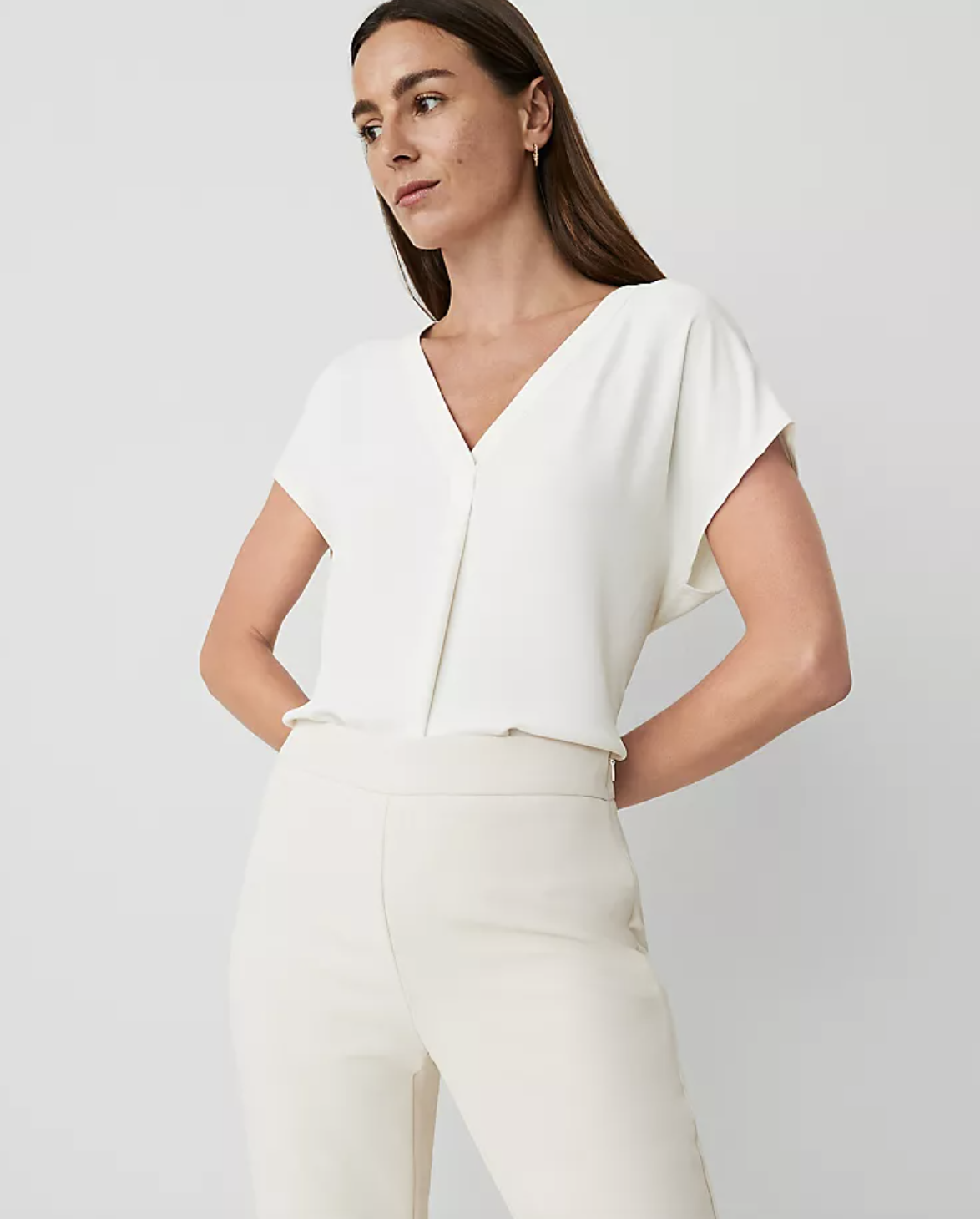 Professional stylist's pick for the Ann Taylor Petite Mixed Media Notch Collar Blouse in white, featuring a crisp v-neckline and a flattering pleat-front detail styled with cream trousers.