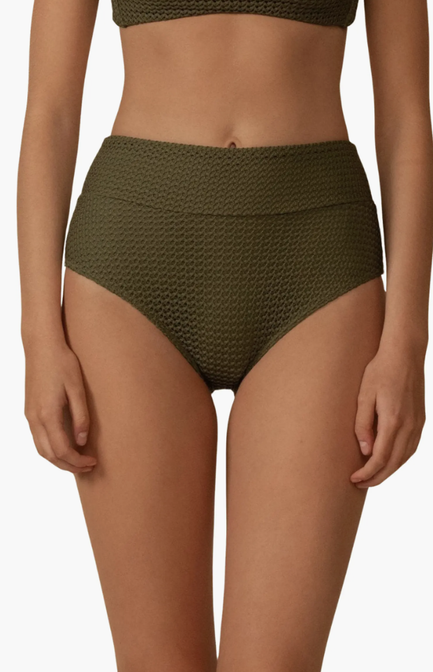 A close-up of a woman wearing olive green high-waisted bikini bottoms with a textured pattern, providing a flattering and supportive fit for a vacation swim wardrobe.