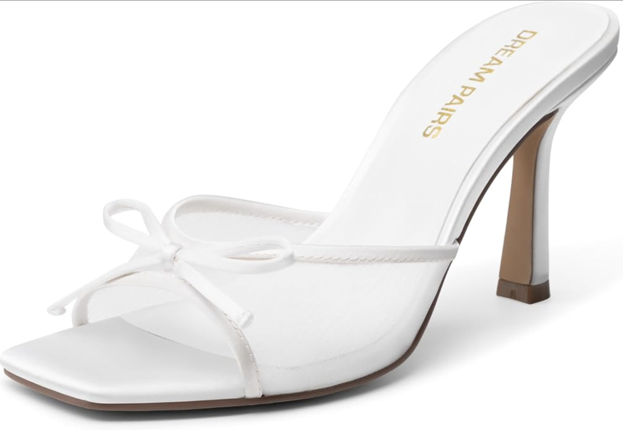 A pair of minimalist white strappy high-heel sandals with a square open toe and delicate bow detailing, styled for a luxury resort evening look.