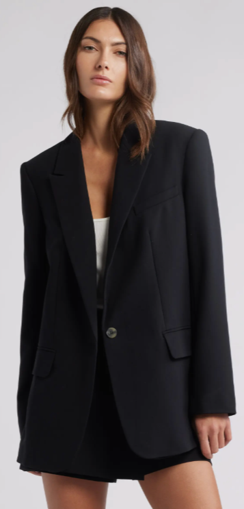 A woman wearing the The Icon Relaxed Blazer, a black oversized blazer styled over a white top, serving as a key layering piece for a 2026 sneakers and jeans outfit.