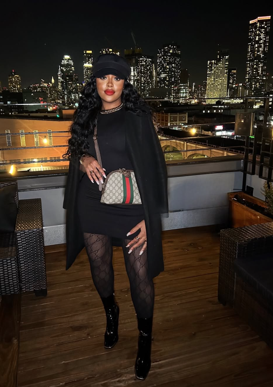 woman styling black patent leather boots with a black blazer dress and patterned tights, providing inspiration for shoes to wear with a little black dress."