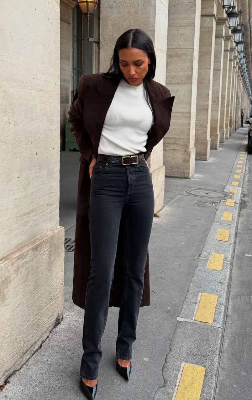 Close up of a woman wearing pointed-toe black heels and straight-leg denim under a long brown wool coat, demonstrating modern classic style.