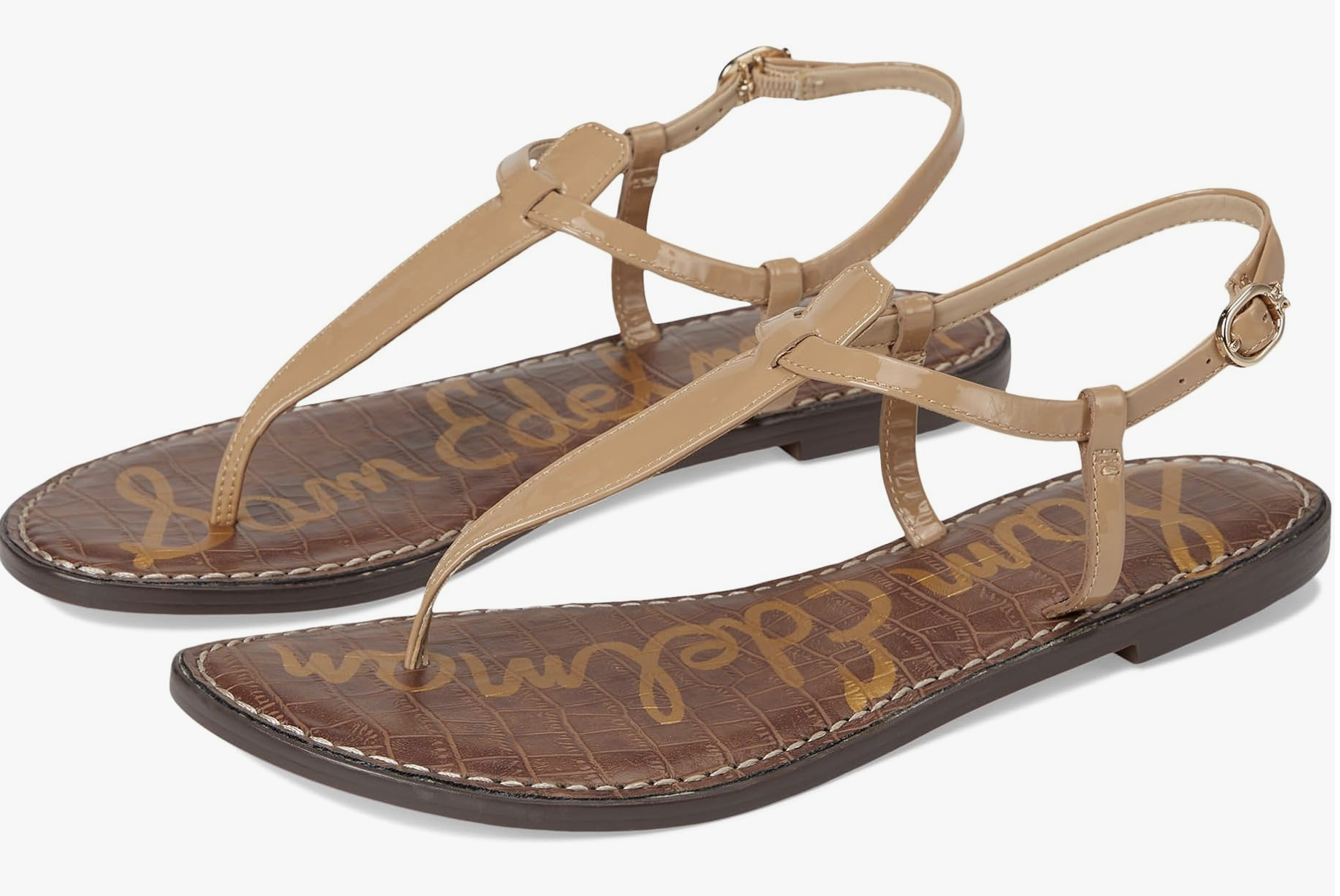 A pair of Sam Edelman Gigi flat thong sandals in tan leather with a slim ankle strap and gold buckle detail on a white background.