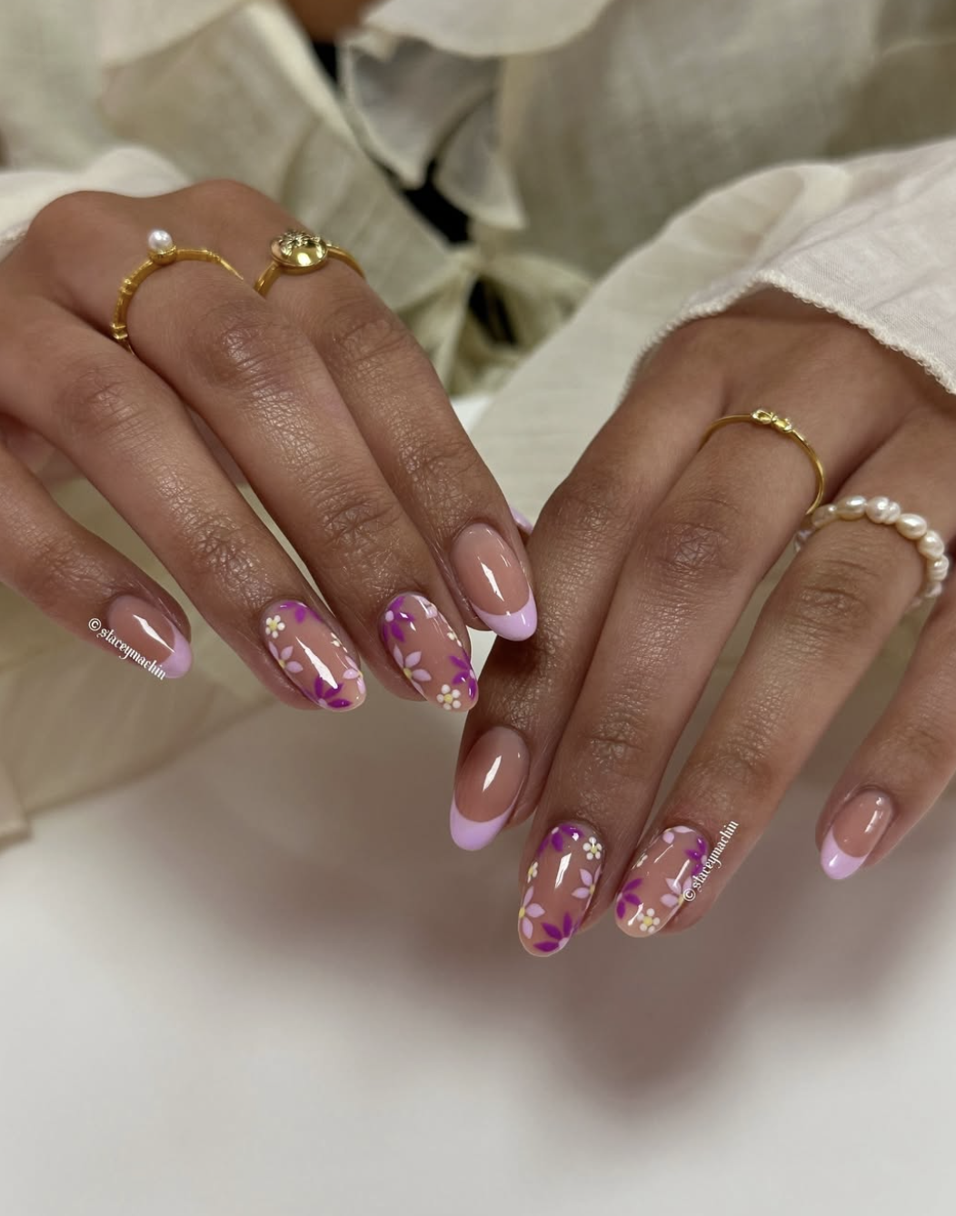 Almond-shaped nails with solid lavender polish and accent nails featuring hand-painted purple and white flowers.
