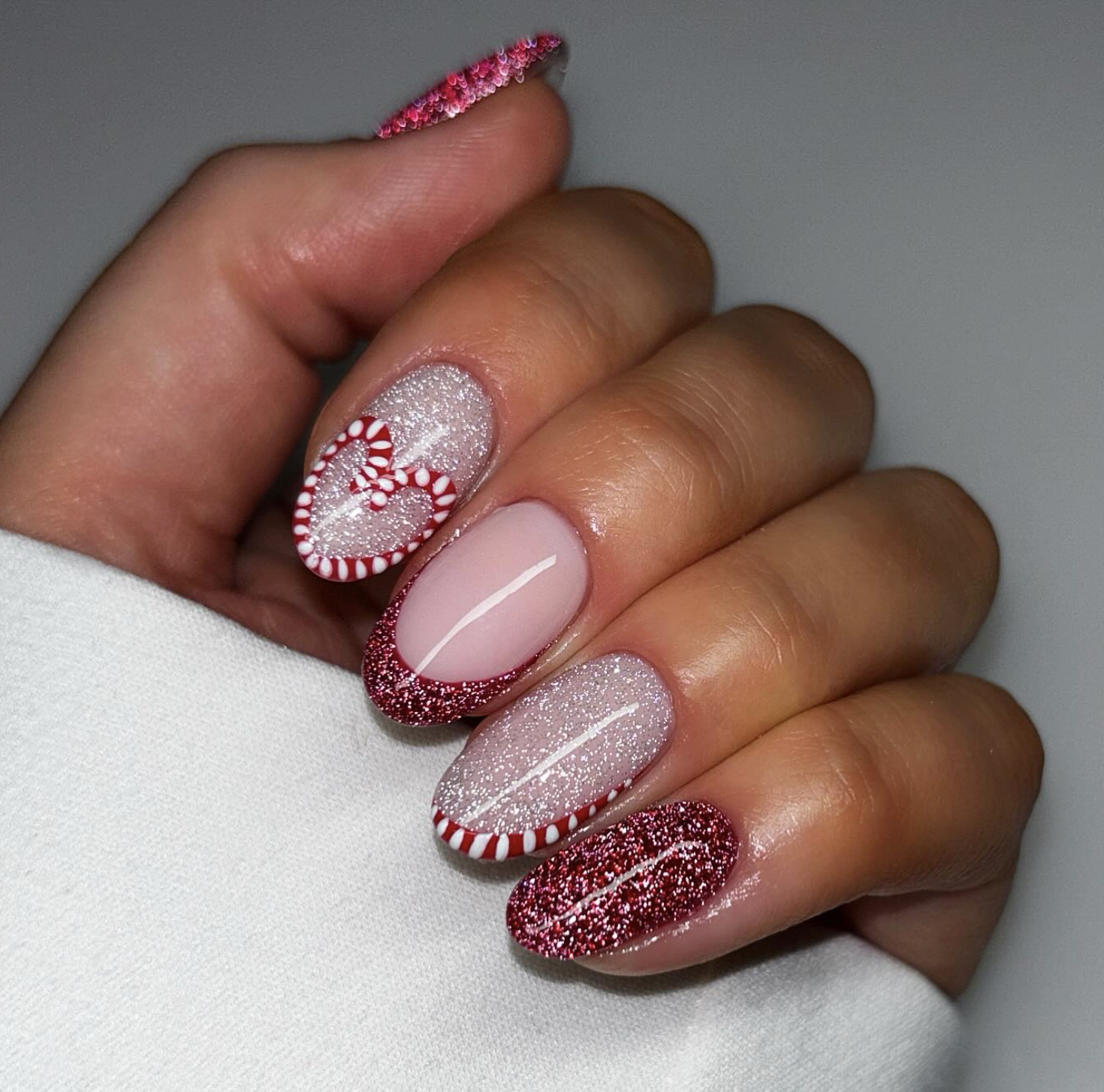 Red glitter and white striped candy cane nails on a sheer base