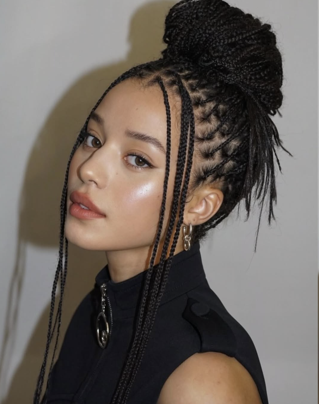 Long braids styled in a high top knot with two face-framing braids left loose.