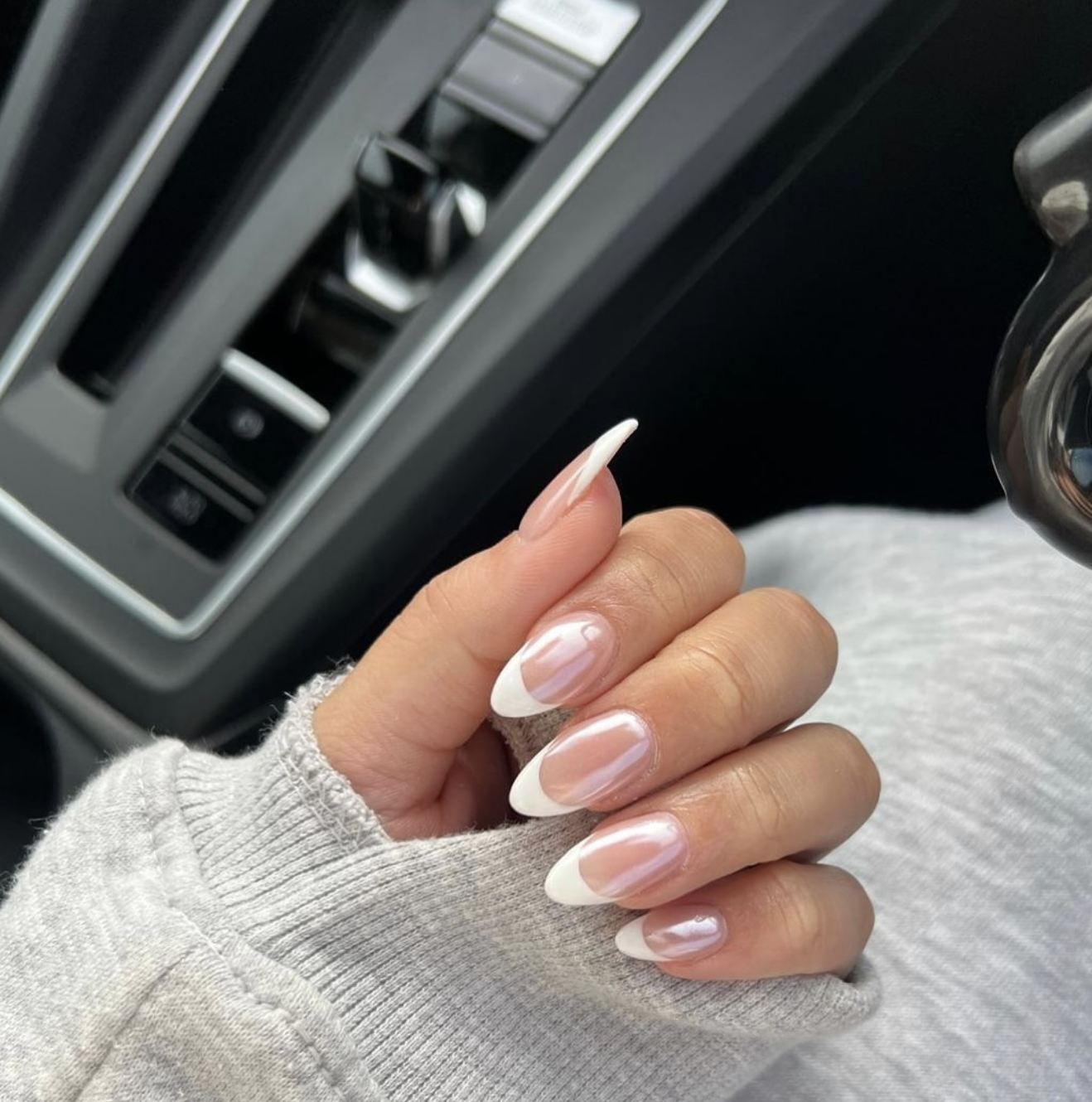 Long almond-shaped nails with a translucent nude base and white French tips, finished with a high-shine pearlescent "glazed donut" chrome overlay.