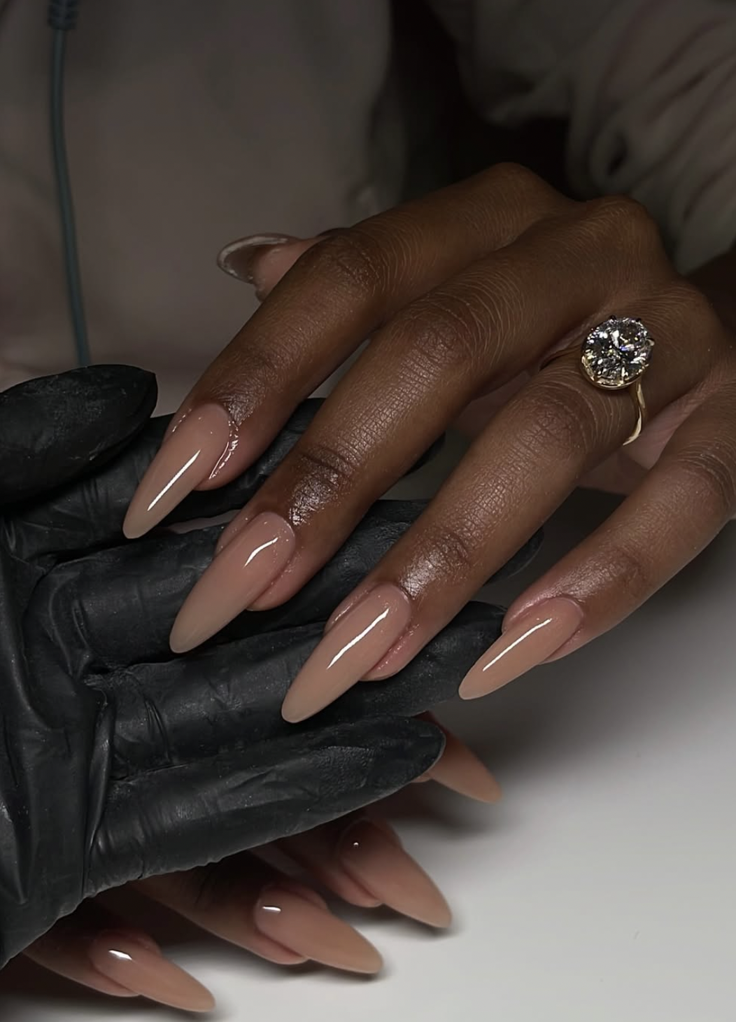 milky caramel nude nails manicure photographed close up on hands. Adjust to accurately describe the finished image.
