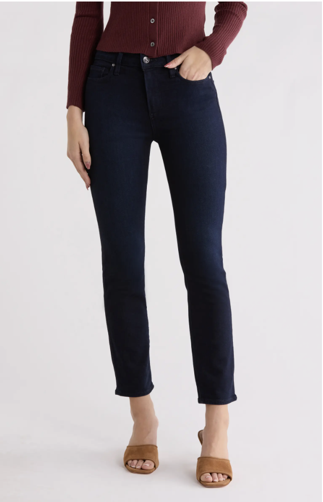 A woman wearing PAIGE Cindy high-waist ankle straight-leg jeans in a dark wash, styled with brown suede heeled mules for a business casual office look.