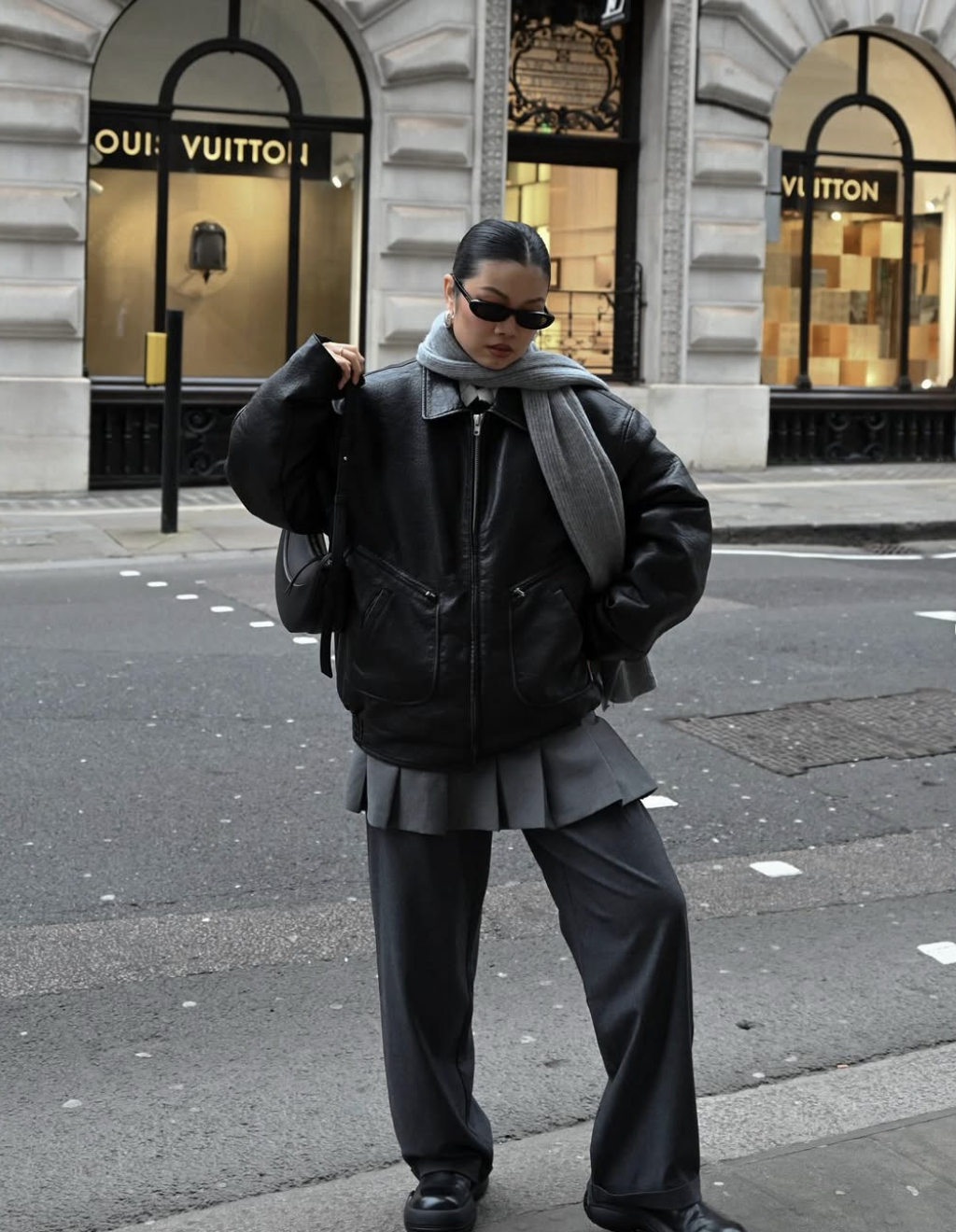 A pro stylist-inspired layering look featuring a grey pleated mini skirt layered over matching wide-leg trousers and a black leather jacket.