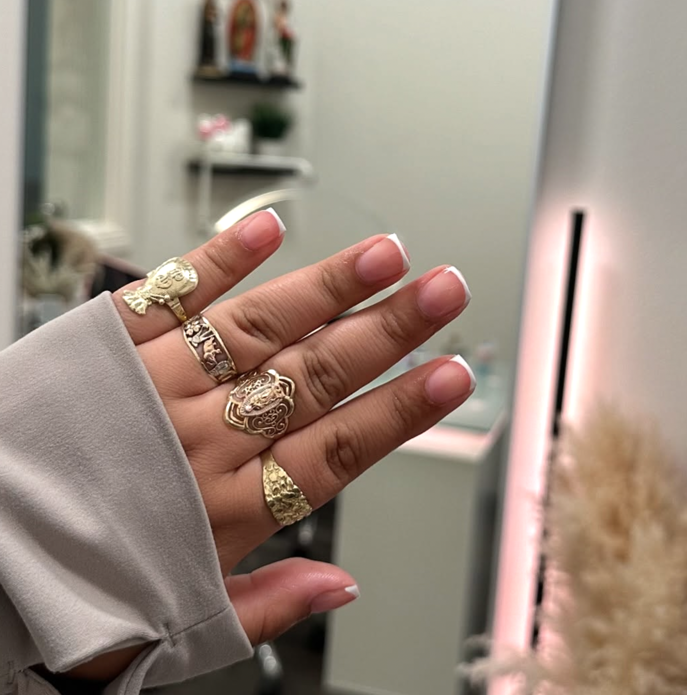 Close-up of a hand featuring a side-swept micro French manicure with thin diagonal white tips over a sheer pink base.